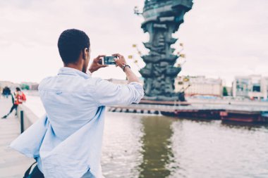 Sosyal ağlarda arkadaşlarınızla paylaşmak için smartphone kamera güzel yeri resmini yapmak afro Amerikalı adam arkadan görünüm görüntüsü. Erkek Gezgin alarak resmi dışında yürüyüş sırasında telefon için
