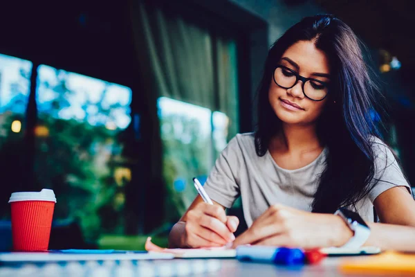Zamyślony Brunetka Student Kobiece Okularach Koncentruje Się Pracę Domową Pisania — Zdjęcie stockowe