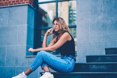 Rahat kıyafet açık havada defada merdivenlerde cep telefon konuşmayı kentsel ayarları arka plan üzerinde dinlenme arkadaşıyla Eyewear güzel genç kadın konuşurken düşünceli hippi kız
