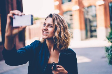 Selfie modern Smartphone Uygulama açık havada kullanarak cep telefonu fotoğraf makinesi yolu ile sokak, mutlu genç kadın blogger alarak resim üzerinde yürüyüş için poz kısa sarı saçlı hippi kız gülümseyerek