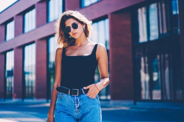 Şehir sokak kopyalama alanı alanı için reklam, yakınındaki şık giyim ayakta açık havada bahar gün kameraya bakarak sırasında dinlenme güneş gözlüklü genç kadın büyüleyici ciddi hipster kız portresi