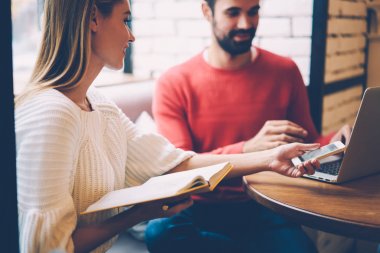 Genç erkek ve dişi hipsters arkadaşlarım netbook kafede Wi-Fi bağlantısı kullanarak birlikte yeni virüsten koruma yazılımı yükleme uygulaması kullanarak dizüstü bilgisayar ile Smartphone dosyaları eşitleme