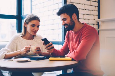Romantik Çift kahve molası birlikte vakit tadını çıkarırken smartphone cep telefonu ile video izlerken gülümsüyor, sakallı adam Tarih sırasında iletişim güzel kız cep telefonunuzda fotoğraf gösterilen