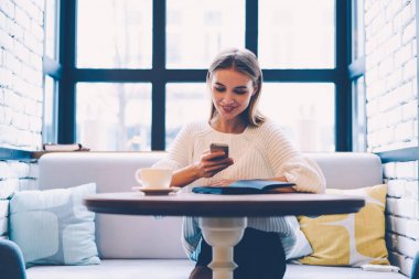 Sohbet online sosyal ağlar, erkek haber smartphone cep telefonu ile kahve sırasında okuma hippi kız sevimli ileti alınırken gülümseyen pozitif genç kadın rahat kafede tatili