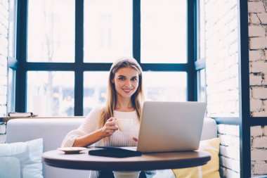 Sıcak kahve Cafe iç güncelleştirmek bilgisayar yazılımı üstünde laptop, müreffeh genç iş kadını serbest zaman olarak sosyal ağlar sohbet sırasında dinlenme zevk molası gülümseyen serbest meslek portresi