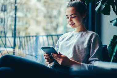 İnternet dijital tablet tarama şirin olumlu hippi kız rahat yerde oturup sırasında wifi için bağlı. Mutlu genç zamana Cafe harcama ise modern teknolojisini kullanarak