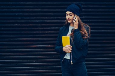 Sevimli genç ile sokulgan yolu ile smartphone uygulama bahar yürüyüş sırasında iletişim şık kıyafet giymiş. Dışarıda dolaşmak ve duvar kopya alanı ile yakın telefonda konuşurken kız öğrenci