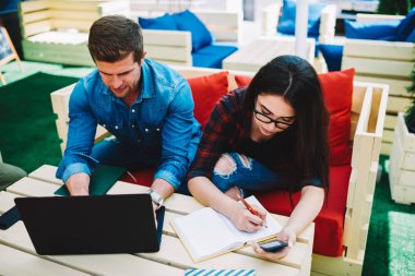 Yetenekli öğrenciler için bilgi ve dijital telefon için yüksek bağlanma searchin modern dizüstü aygıtı kullanarak eğitim semineri için hazırlanıyor hızlı internet açık havada kafede oturan verimli çalışması için