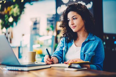 Yararlı izlerken çekici yetenekli öğrenci webinar Web sitesindeki eğitim ve bazı gösterimler kafede oturan not etmek için yapmak. Web sayfasında laptop Haberler okuma ve bilgi kaydetme hippi kız