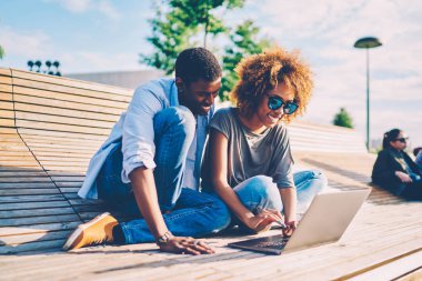 Afro Amerikan çift sahip eğlenceli birlikte mutlu koyu tenli kız kıvırcık saçlı yazarak banktaoturuyor ağlarda bilgi aramak üstünde laptop rezervasyon online oturan adam Bilet