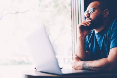 Yakışıklı düşünceli erkek girişimci yaklaşan başlangıç projesi için yaratıcı fikirler düşünmeye casual giyim giymiş. Genç hipster adam kapalı oturma sırasında durulması gözlükler