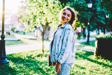 Park açık havada eğlence zaman ve kopyalama alanı alanı yeşil promosyon zemin üzerine güneşli hava zevk yürüyüş denim giyim giymiş neşeli şık öğrenci yarım uzunluk portresi