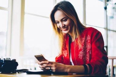 Yeni fotoğraf uygulaması üzerinde modern telefon aygıtı yükleme mutlu genç profesyonel fotoğrafçı. Pozitif kadın blogger uploading fotoğraf ve videoların kendi web sayfası üzerinden yüksek hızlı internet