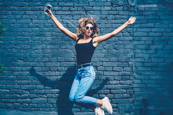 Счастливая Молодая Женщина Весело Прыгающая Высоко Рекламном Фоне Слушая Музыку — стоковое фото