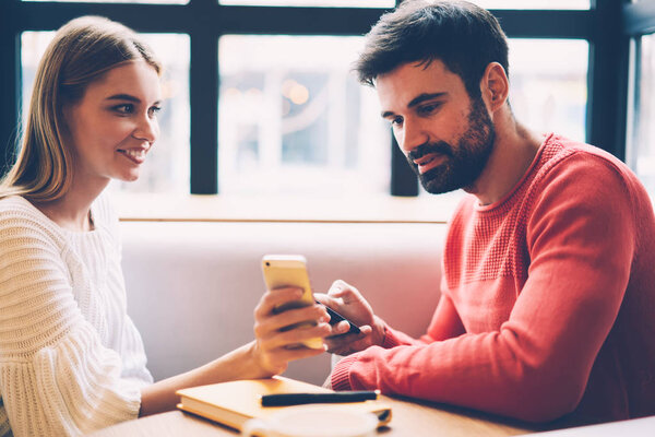 Счастливая молодая девушка хипстер показывая ее парень веб-магазин делает покупки вместе с помощью приложения на смартфоне, пара влюбленных проводить время вместе поиск ресторан для знакомств в Интернете
