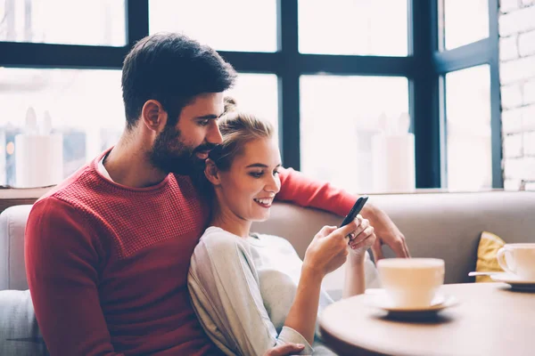微笑的时髦女孩显示商店的网页与项目买给他的男朋友花时间在一起 情侣相爱在咖啡厅预订电影的门票通过智能手机应用程序休息 — 图库照片