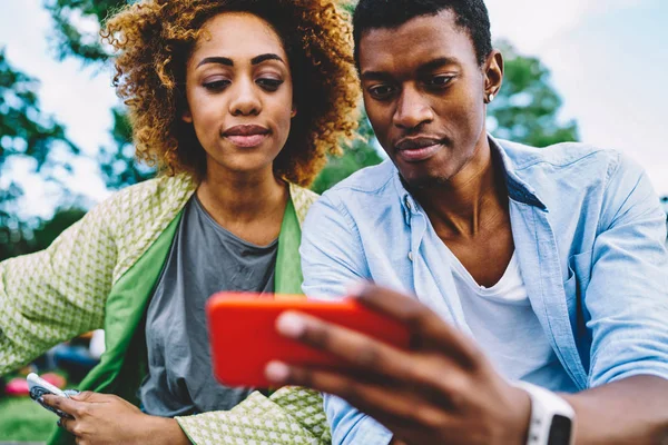 思慮深いアフロ アメリカ人男性と女性の友人スマート フォン 一緒に時間を過ごす Web サイトが携帯電話を介してオンライン予約の価格についての情報を読んで愛のカップルで映画を見て — ストック写真