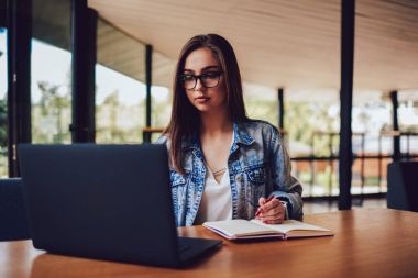 Şık gözlük yüksek kablosuz için modern dizüstü bilgisayar bağlantı, serbest çalışma akıllı genç kadın hızda internet. Bilgi Web sitelerinde arama ve Not Defteri'nde yapma öğrenci