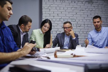 Deneyimli tasarımcıların inşaat sırasında işbirliği içinde ofis iç planlama kroki analiz. erkek ve kadın grup fikirleri tartışmak ve görüşleri çalışma işlemi sırasında paylaşım yaratıcı mimarlar