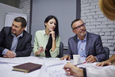 Ortak proje üzerinde işbirliği fikirleri tartışmak çalışan grubu gülümseyerek. Ekip işbirliği oluşturma yeni office skeçler binasında oturma planlama profesyonel mimarlar