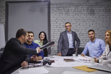 Yönetim ekibi çalışma birlikte oturma tablo çizimler ve verimli çalışması için ekipman ile tanışma. Erkek ve dişi Mimarlar office konferans sırasında Blueprint yapı üzerinde işbirliği yapma