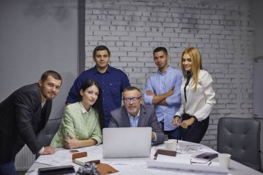 Yarım uzunluk portre grup yetenekli çalışanların sorunları çözme ve planları ile çalışma sırasında kameraya bakıyor. Uzmanlar teknolojisini kullanarak reklam kampanyası geliştirmek pazarlama ekibi
