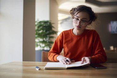 Üniversite kampüsü içinde defterini yazma ödev görevleri yerine getirmeye şirin saç modeli ile rahat kıyafet içinde çekici genç kız öğrenme ders için Strateji planlama çalışma kız öğrenci konsantre