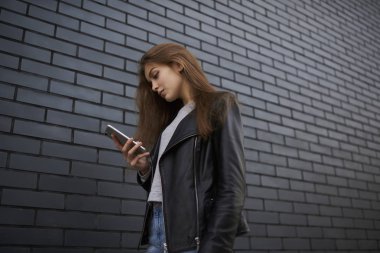 Kopyalama alanı alanı üzerinde gezinme yolu ile kullanma smartphone ayakta üzerinde gezinme turist şık kıyafet açık havada, vakit sosyal ağlardan video izlerken dalgın kız öğrenci giymiş