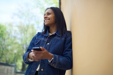 Neşeli afro Amerikalı genç kadın telefon açık havada, modaya uygun Kot ceket bloglama sosyal ağlar bahar weathe zevk mutlu siyah modeli dinlenme üzerinde tablo Cafe uygulaması aracılığıyla rezervasyon