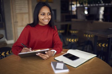 Kafe iç otururken gülümseyen afro Amerikan grafik tasarımcı çizim taslak çalışma günü yazılı denetim hedef listesi planlama koyu tenli Müdürü büyüleyici yaratıcı fikirler üzerinde konsantre