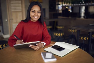 Günlük zamanlama, yetenekli koyu renkli grafik tasarımcı çizim kroki olarak planlama malzeme ile tahta masada oturan çalışma süreci zevk yetenekli afro Amerikan İdari İşler Müdürü
