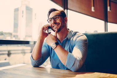 Neşeli işadamı cep telefonunuzda kafe, yakışıklı sahibi başlangıç başarısı meslektaşım ve tartışarak artan popülerlik ve gelir ile tartışan mola dinlenme sırasında arkadaşıyla konuşuyor