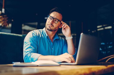 Web üzerinde bilgi arama başlangıç için yaratıcı fikir üzerinde durulması dalgın yakışıklı işadamı. Eyewear mesafe iş hafta sonları hakkında rüya ile kafede oturan genç girişimci