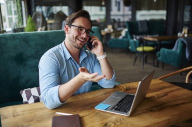 Başlangıç için fikirler cep telefonunuzda konuşurken meslektaşı ile tartışırken gözlük müreffeh bir iş adamı. Genç erkek bağımsız yazılım dizüstü compute üzerinde güncelleştirilirken istemci desteği hizmeti başvurun