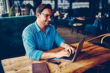 Kafe iç yazarak metin yayın laptop, trendy gözlük iş gezisi planlama Web sitesinde rezervasyon yapmak başarılı erkek girişimci çalışan profesyonel erkek serbest meslek