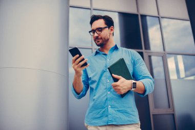 Açık havada, duran genç yöneticisi konumları online haritalar üzerinde arama için smartphone uygulama kullanarak toplantı düzenlemek için meslektaşım mobil yakışıklı işadamı arama numarasına