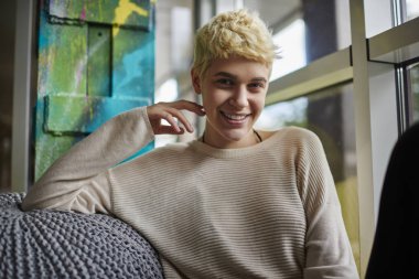 Coworking uzayda serbest zaman sırasında dinlenme trendy kısa saç modeli ile neşeli hippi kız portresi, beyaz modeli büyüleyici boş zamanlarınızı kapalı keyfi moda rahat kıyafetler giymiş