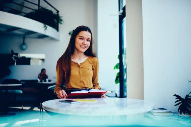 Vakit modern üniversite kitaplığında yeni bilgi, modern coworking uzayda oturan edebiyat zevk mutlu kitap sevgilisi öğrenme otodidakt üzerinde olumlu esmer öğrenci portresi