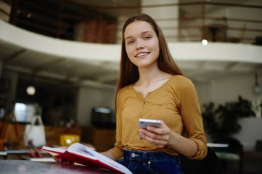 Mobil arkadaş kafede, kitap okumak ise sosyal ağlar üzerinden smartphon serbest zaman blogging zevk mutlu hippi kız sohbet üzerinde ileti gönderme gülümseyen öğrenci portresi
