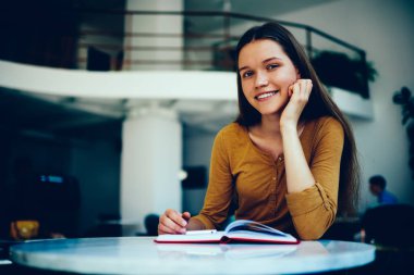 Esmer hippi kız zevk edebiyat hobi üzerinde boş zaman harcama gülümseyen ilginç kitap modern Kitaplığı ' nda sınavlarına hazırlık okurken kameraya arayan büyüleyici öğrenci portresi