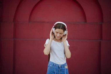 Açık havada, t-shirl markası dinleme musi için kopya alanı ile neşeli hippi kız ayakta ses kalitesi ile modern kulaklık üzerinden çalma listesindeki kompozisyon zevk çekici teen meloman