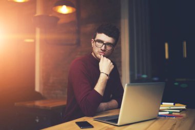 Düşünceli profesyonel grafik tasarımcı düşünme hakkında uzaktan dizüstü bilgisayar başında çalışırken iş uygulamak için fikirler. Masada oturan sırasında durulması gözlük emin girişimci