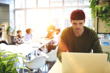 Proje uygulaması aracılığıyla modern aygıtta oluşturma online iş ofis, yetenekli web tasarımcısı coworking oturan bilgisayar yazılımı güncelleştirmek için dizüstü bilgisayar kullanan düşünceli erkek programcı konsantre