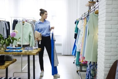 Çekici trendy giyim mağaza seçerken, profesyonel stilist müşteri seçimi tasarımcı dükkanda konsantre trendy görünümünü oluştururken uygun kavram kullanarak kadın müşteri giyinmiş 