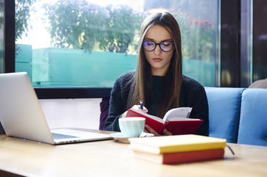 Trendy Eyewear edebiyat bilgileri analiz ciddi kız öğrenci ev ödevi görevi, akıllı hippi kız kafe iç Wi-Fi erişimi ile rapor hazırlama kitap okuma yapmaya konsantre 