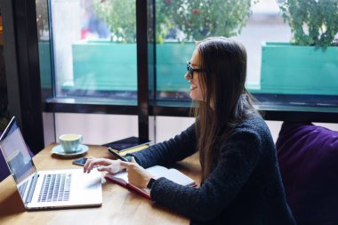 Yaratıcı iş para online çalışma serbest üzerinde kazanç kahve molası, neşeli blogger dinlenme ağdan komik videolar izlemek için dizüstü bilgisayar kullanan olumlu esmer hippi kız memnun