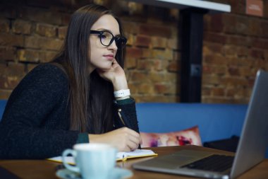 Yetenekli genç öğrenci kafe iç kurs için araştırma yapma web sayfasındaki bilgileri belirterek. Eğitim webinar web modelleme Not Defteri'nde Yazma ipuçları ve fikirler üzerinde izlerken yetenekli tasarımcı