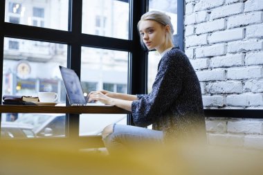 Çekici dalgın freelancer web sayfası düşünmeye çalışırken dizüstü bilgisayarda yazarak Cafe iç, yetenekli yazarı yaratıcı çözüm için pazarlama kampanyası geliştirmek için wifi bağlı