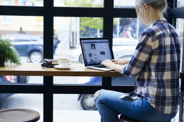 Yetenekli web tasarımcısı sahte ile dizüstü bilgisayar uygulama kullanarak online iletişim geribildirim tipik görünümü profesyonel metin yazarı kafede oturan uzak iş yapmak için ekran yukarı geri