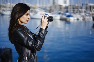 Esmer fotoğrafçı resmi güneşli günde liman içinde yürüyüş, turist alarak fotoğraf yolu ile vintage fotoğraf makinesi ayakta promosyon arka plan bulanık yakınındaki büyüleyici kentsel ayarı yapma konsantre
